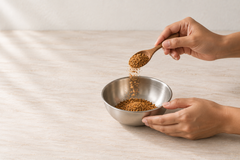 Flax and Garlic Wellness Sprinkle powder being lifted on a wooden spoon